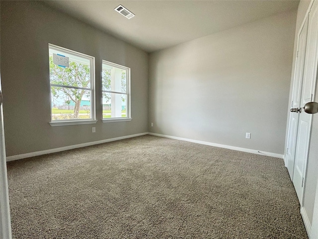 carpeted empty room featuring baseboards and visible vents