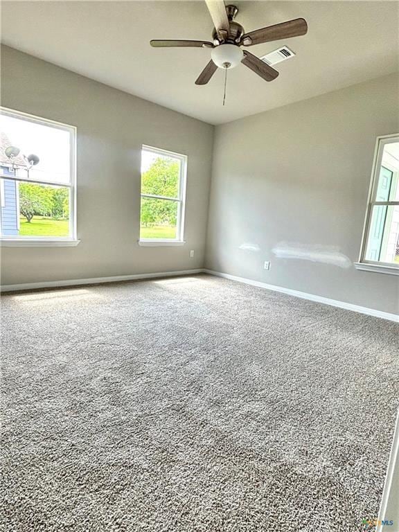 spare room featuring carpet floors, a ceiling fan, baseboards, and a healthy amount of sunlight