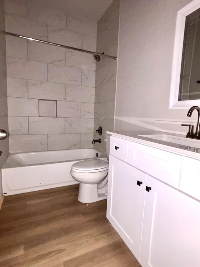 bathroom with vanity, washtub / shower combination, wood finished floors, and toilet