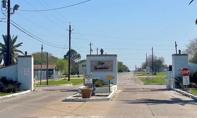 view of road with traffic signs, a gated entry, and curbs