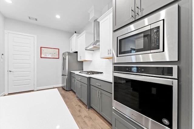 kitchen with visible vents, light countertops, gray cabinets, light wood finished floors, and stainless steel appliances