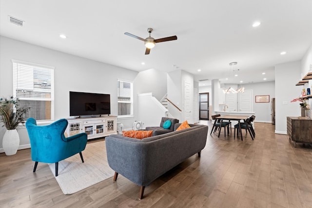 living room with recessed lighting, plenty of natural light, stairs, and wood finished floors