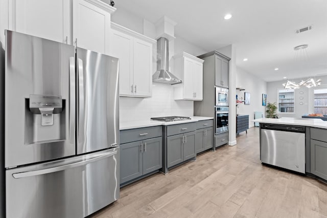 kitchen featuring visible vents, gray cabinets, appliances with stainless steel finishes, and wall chimney range hood