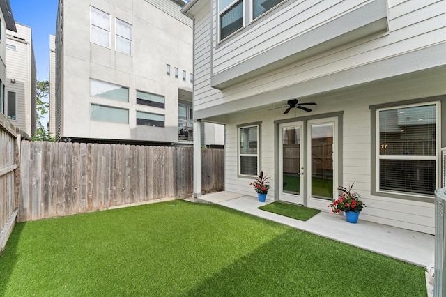 view of yard with a ceiling fan, french doors, and a fenced backyard