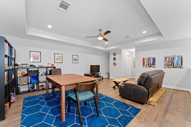dining room featuring ceiling fan, a tray ceiling, visible vents, and wood finished floors