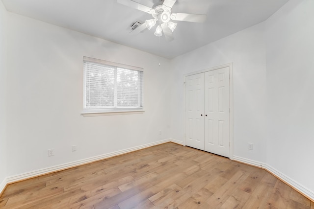 unfurnished bedroom featuring a ceiling fan, baseboards, a closet, and light wood-style floors