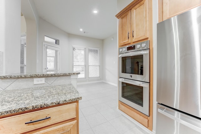kitchen with light stone countertops, arched walkways, stainless steel appliances, recessed lighting, and light tile patterned floors