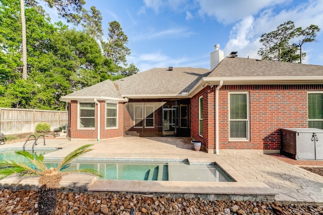 rear view of property featuring fence, a patio, a chimney, a sunroom, and brick siding
