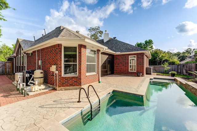back of house featuring a fenced backyard, a patio, a chimney, and brick siding
