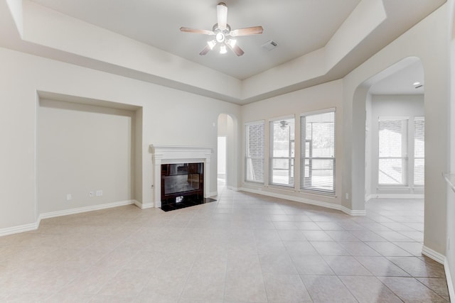 unfurnished living room with visible vents, baseboards, arched walkways, a ceiling fan, and light tile patterned floors