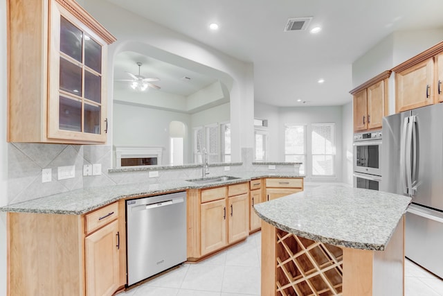 kitchen featuring light brown cabinetry, a sink, stainless steel appliances, a ceiling fan, and visible vents