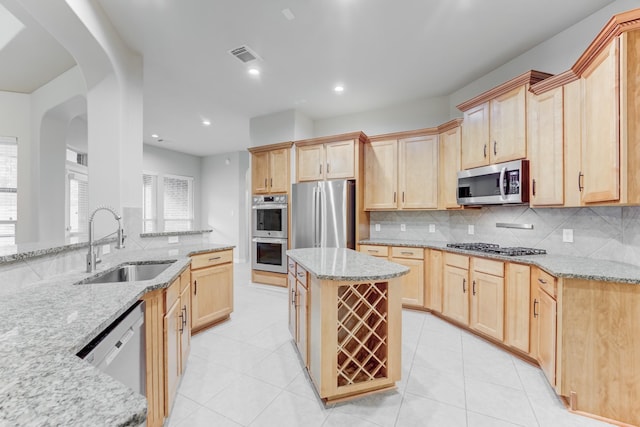 kitchen with visible vents, a sink, light stone counters, light brown cabinets, and stainless steel appliances