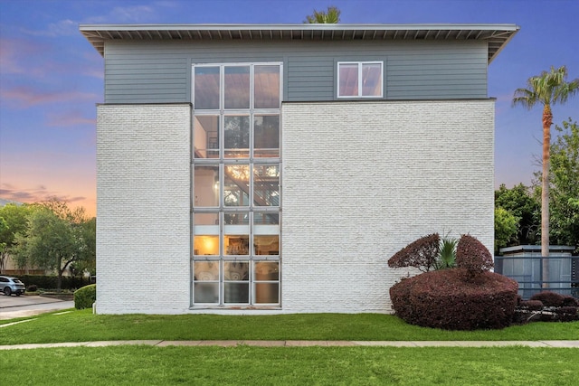 view of side of home featuring a lawn and brick siding