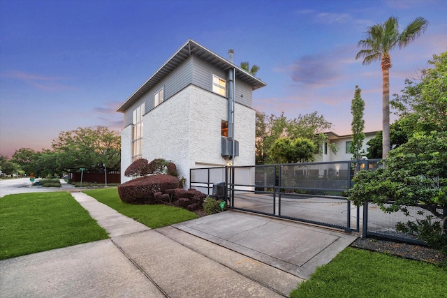 view of side of property featuring driveway, a lawn, a gate, fence, and an attached garage