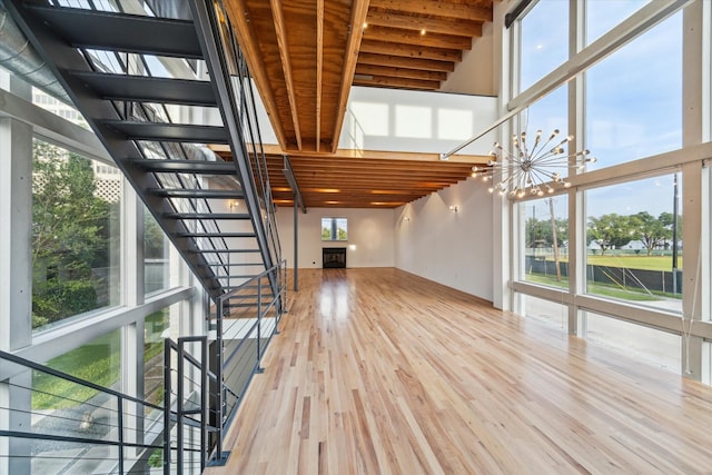 unfurnished living room featuring stairs, a fireplace, wood finished floors, and a towering ceiling