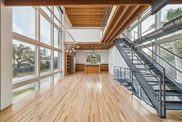 unfurnished living room featuring light wood finished floors and a towering ceiling