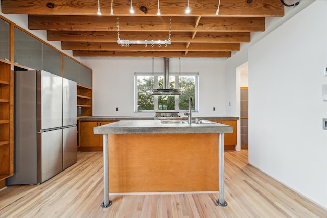 kitchen featuring freestanding refrigerator, open shelves, beam ceiling, light wood-style floors, and a sink