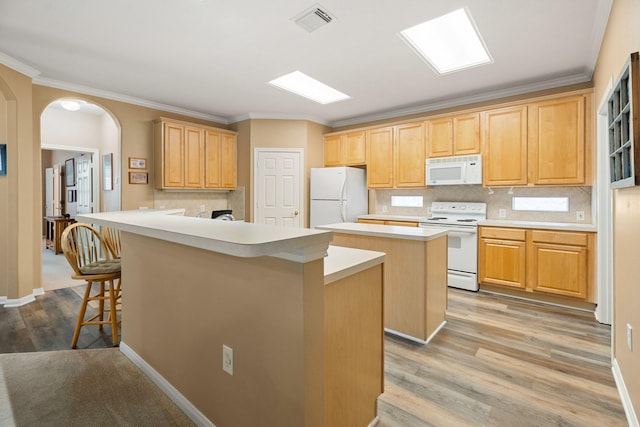 kitchen with a kitchen bar, visible vents, a center island, tasteful backsplash, and white appliances