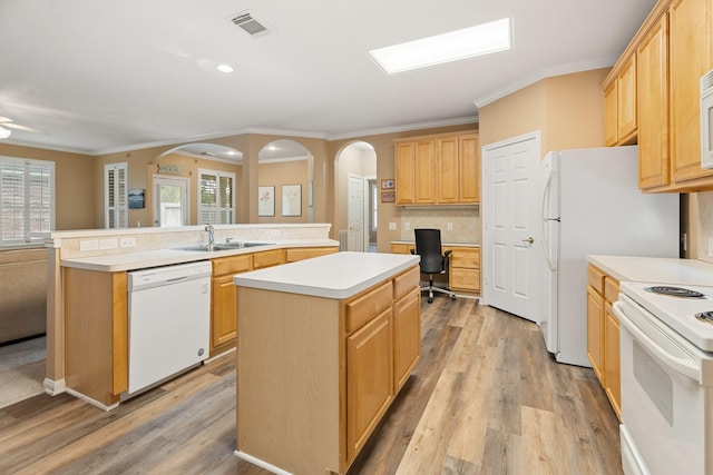 kitchen featuring ornamental molding, a sink, a kitchen island, white appliances, and arched walkways