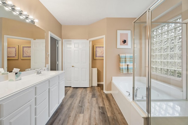 full bath featuring vanity, a shower with door, a bath, and wood finished floors