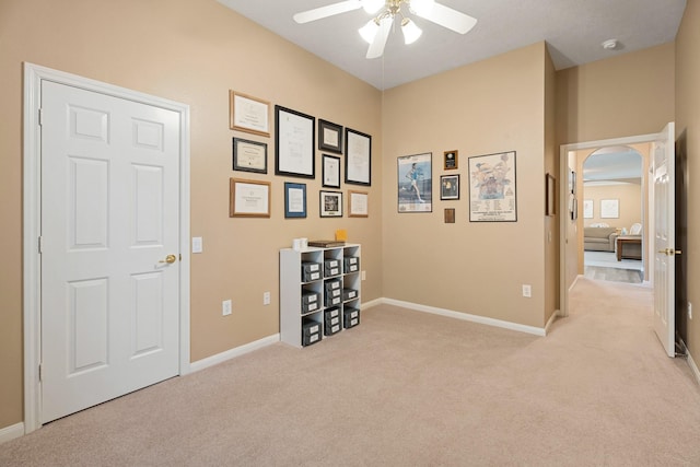 interior space with baseboards, light carpet, and arched walkways
