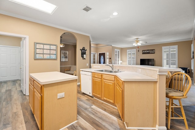 kitchen featuring white dishwasher, a ceiling fan, a center island with sink, and ornamental molding