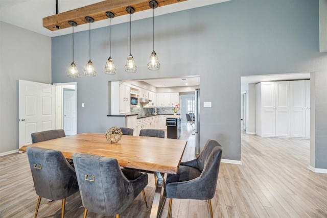 14123 Hillvale Dr, Houston, TX 77077 - dining room featuring a high ceiling, baseboards, and light wood finished floors