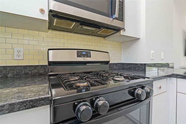kitchen with appliances with stainless steel finishes, white cabinetry, dark countertops, and tasteful backsplash