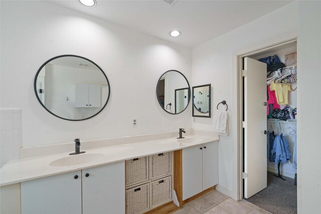 full bathroom with double vanity, a spacious closet, tile patterned flooring, recessed lighting, and baseboards