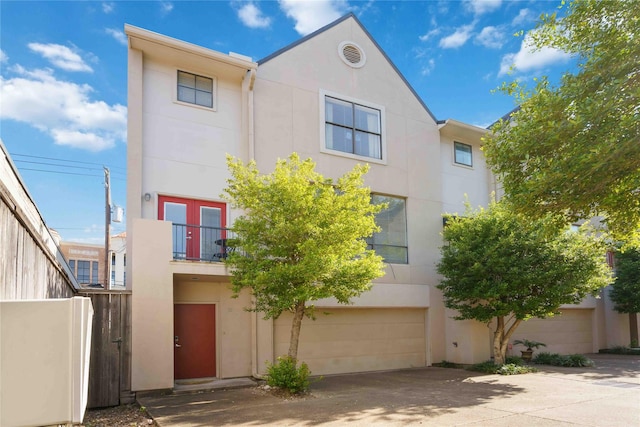 multi unit property featuring a garage, stucco siding, concrete driveway, and a balcony