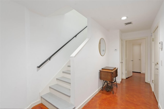 staircase featuring finished concrete flooring, recessed lighting, and baseboards