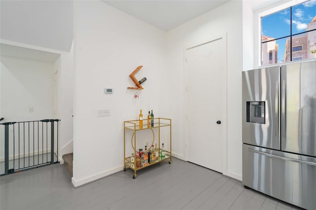 interior space with stainless steel fridge, wood finished floors, and baseboards