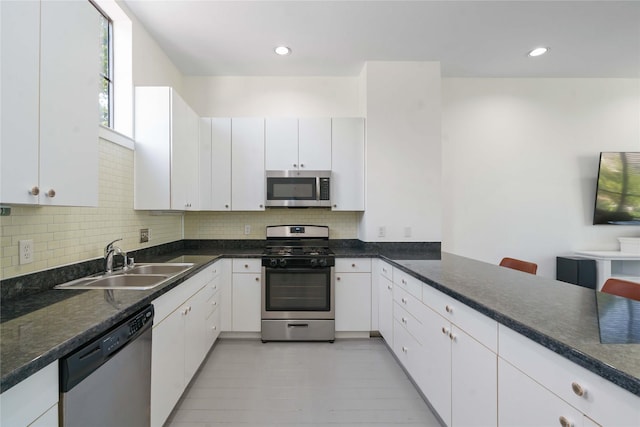 kitchen with stainless steel appliances, a sink, backsplash, white cabinetry, and recessed lighting