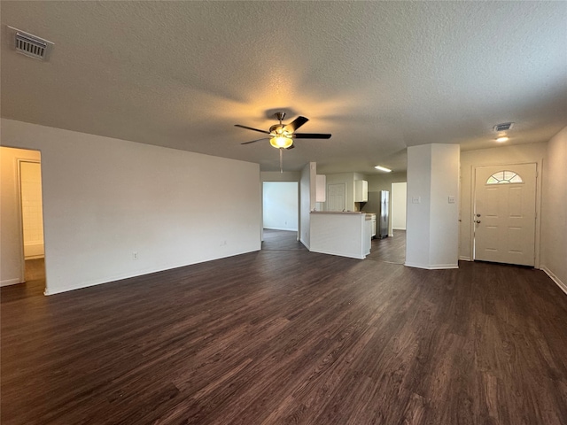 unfurnished living room with baseboards, ceiling fan, dark wood finished floors, and a textured ceiling