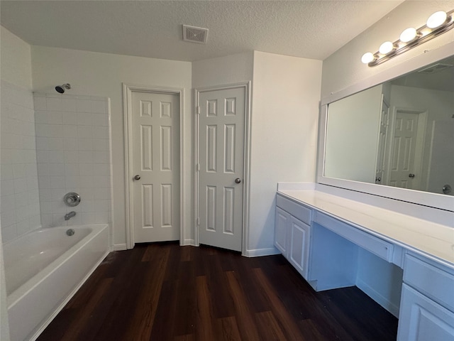 bathroom featuring visible vents, tub / shower combination, wood finished floors, and vanity