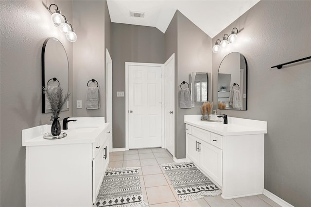 bathroom with a sink, tile patterned flooring, baseboards, two vanities, and visible vents
