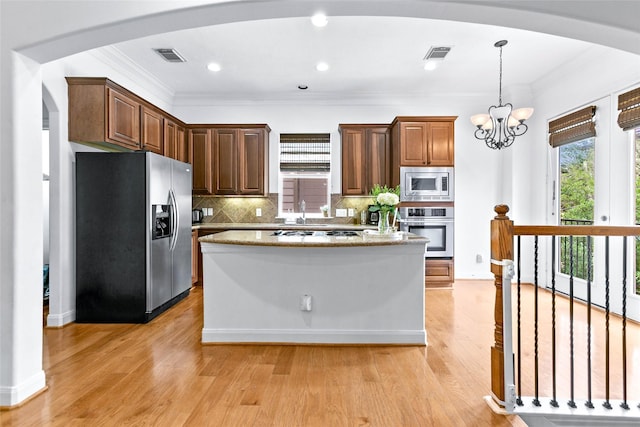 kitchen with a healthy amount of sunlight, appliances with stainless steel finishes, decorative backsplash, and arched walkways