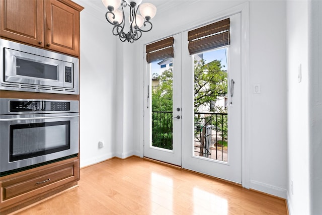 entryway with baseboards, a chandelier, and light wood finished floors