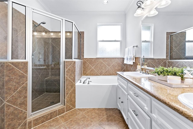 bathroom with crown molding, tile walls, tile patterned flooring, a shower stall, and a sink