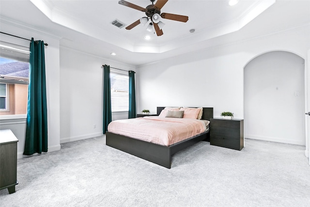 bedroom with ornamental molding, a tray ceiling, and visible vents