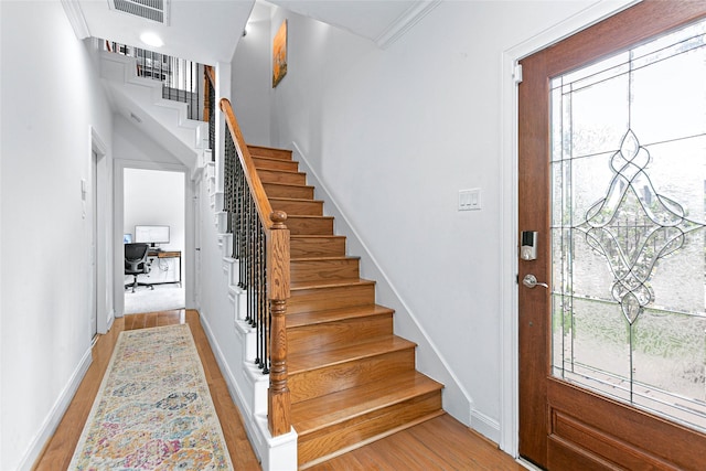 entryway with visible vents, light wood-style flooring, stairs, and baseboards