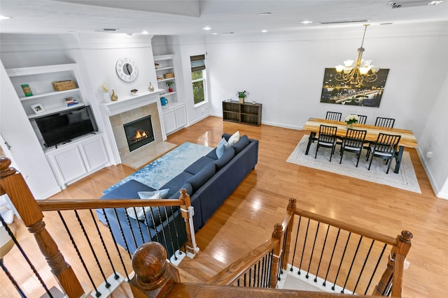 living area with light wood-style floors, built in features, an inviting chandelier, and baseboards