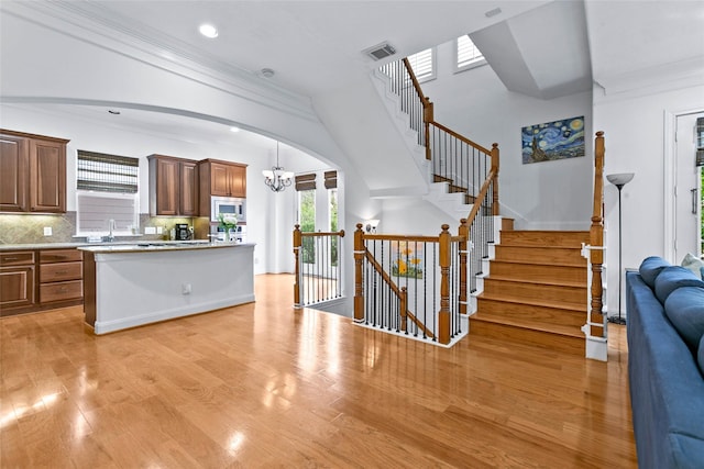 kitchen with visible vents, decorative backsplash, open floor plan, light wood-type flooring, and stainless steel microwave