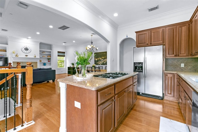 kitchen with arched walkways, appliances with stainless steel finishes, light wood finished floors, and visible vents