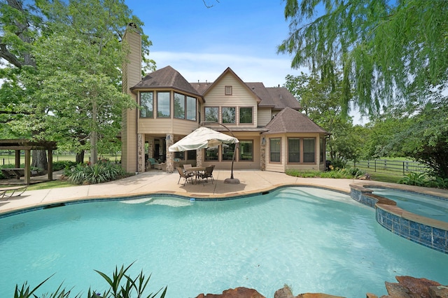 view of pool with a pergola, a patio area, fence, and a pool with connected hot tub