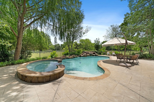 view of pool featuring a patio area, a pool with connected hot tub, and fence