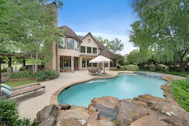 view of swimming pool with a patio area, fence, and a pool with connected hot tub