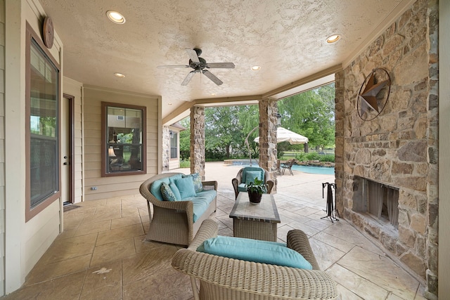 view of patio / terrace with an outdoor living space with a fireplace, ceiling fan, and an outdoor pool