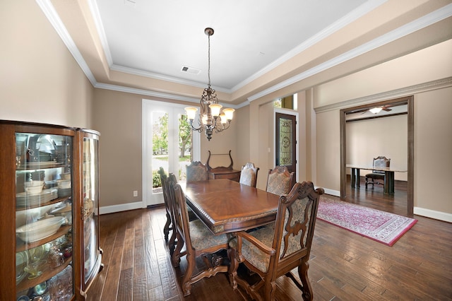 dining area with a chandelier, dark wood finished floors, ornamental molding, baseboards, and a raised ceiling