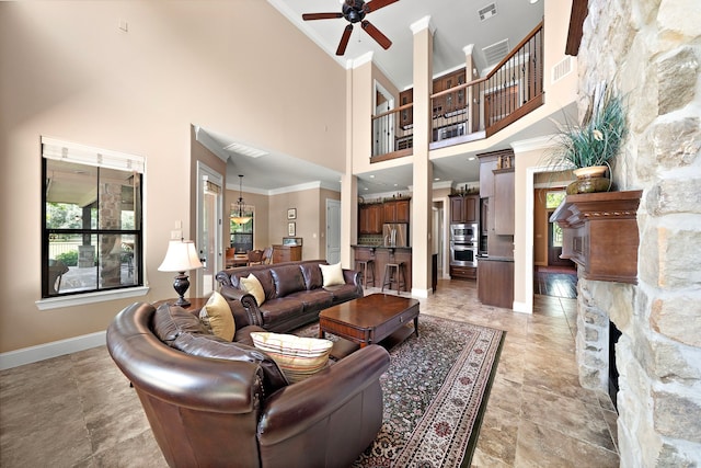 living room with a ceiling fan, crown molding, a high ceiling, baseboards, and a fireplace